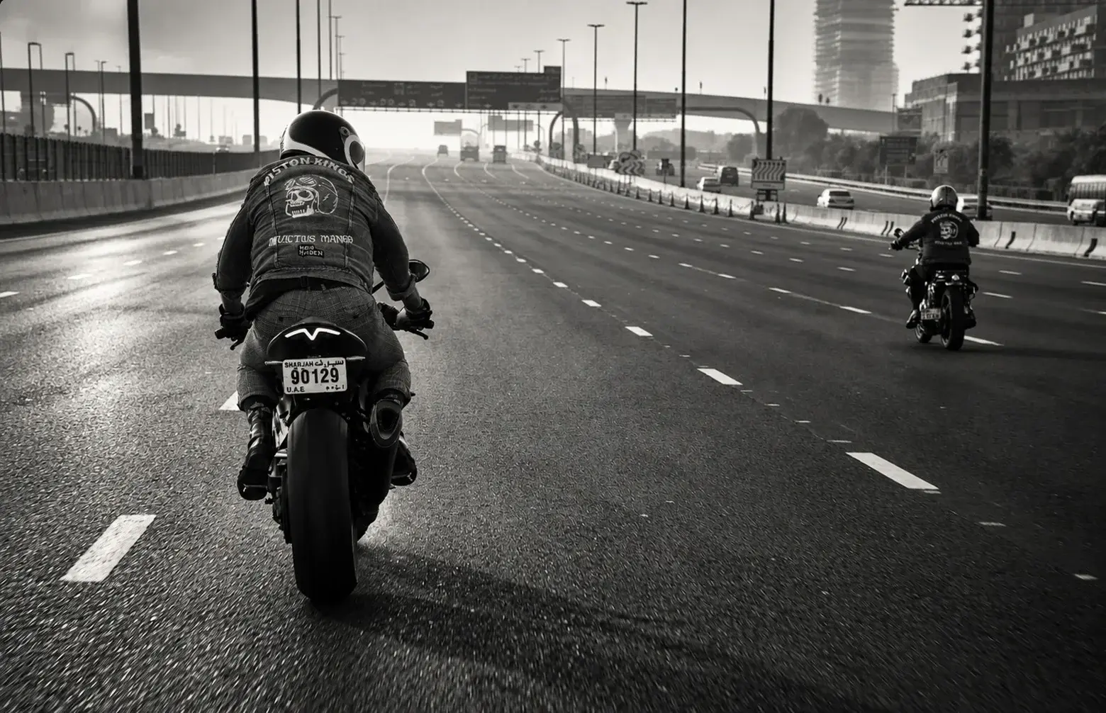 Two Piston Kings riders travelling along a Dubai road, photographed in black and white.